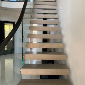 Bespoke floating staircase Oak treads light grey lacquered with contrasting black handrails